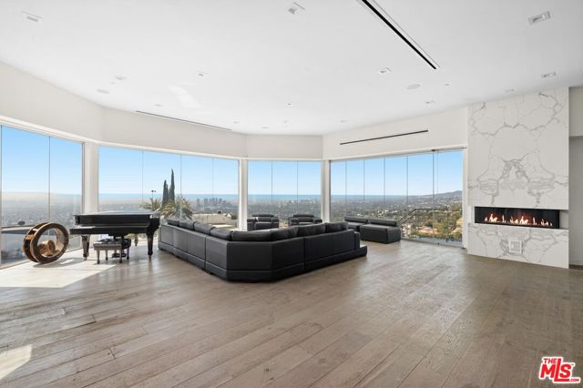 Above the social stirs of Sunset Blvd, you'll find this trophy estate. Standing three stories high and encapsulated in frameless glass windows, this is the optimal opportunity to create your dream home on one of West Hollywood's most sought-after streets. Light projects into the open format living area, where you'll take in vivacious views from the Downtown skyline to the iconic oceanfront. A modern kitchen completes the space, accented with calacatta quartzite countertops, matching backsplash, and luxe appliances. Four generously-sized ensuite bedrooms occupy the main house, each with sprawling views; as well as a flexible fifth room, currently converted into a plush home theater. A self-contained guest house sits onsite, equipped with its own kitchen, separate entry and garage access. Designed for entertaining, a 2,500 square foot deck with an inset pool serves as a prime vantage point to overlook the city, as a wrap-around balcony provides striking views from every angle. This home and landscape are the perfect canvas to add the finishing touches that make the space your own. Selectively renovated with opulence in mind, additional amenities include an Italian imported elevator and full automation system for the ultimate smart home experience. This rare find is comfortably secluded while soaking in the cityscape in order to offer the best of modern luxury.