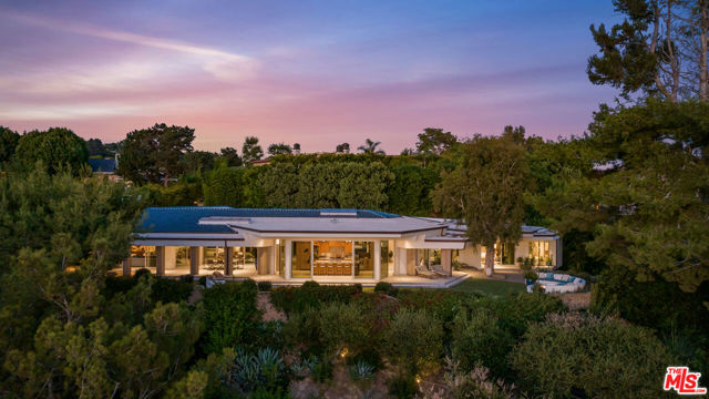 Nestled in the heart of Bel Air, this exceptional California Mid-Century Modern gem weaves together the threads of history, architecture, and luxury living. Originally envisioned by Matthew Leizer for the iconic musician, Robby Krieger of The Doors, this exquisite 4 bed | 4.5 bath property represents an ode to architectural brilliance. Expertly renovated in 2018 with the utmost attention to detail, it effortlessly blends the past and present. Spanning nearly 1.4 acres, this ultra-private gated estate offers breathtaking panoramic vistas from the Getty Museum to the Pacific Ocean. The hexagonal-shaped residence, paying homage to architectural visionaries, Frank Lloyd Wright and John Lautner, creates a space where right angles are forgotten and replaced by captivating vignette views and playful plays of light. Vaulted corked ceilings, a gourmet kitchen, and Terrazzo floors underscore the meticulous craftsmanship at play. With history gracing its walls, an original Frieze interpretation of The Doors adorns the living space. Enjoy an effortless indoor-outdoor lifestyle that harmonizes with nature's rhythm. A variety of entertainment spaces cater to your every mood, such as a serene courtyard pool, a well-appointed bar, a rejuvenating spa, and a cozy outdoor fire pit. This Bel-Air sanctuary, rich in Hollywood music history, is your ultimate escape from city living. With its unrivaled charm and timeless elegance, it invites you to become part of its story.