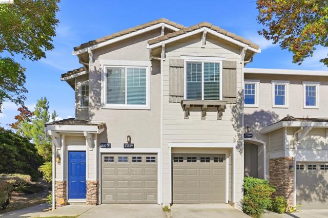 Contemporary exterior featuring a bright blue entry door, stone veneer accents, two attached garages, and decorative window shutters