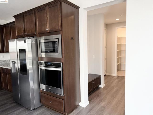 Kitchen with dark brown cabinets, stainless steel appliances, dark wood finished floors, and recessed lighting