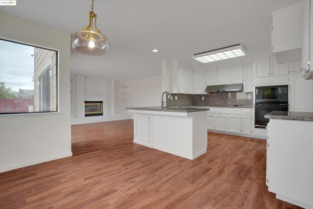 Kitchen with a peninsula, decorative backsplash, white cabinets, a fireplace, and dark stone countertops