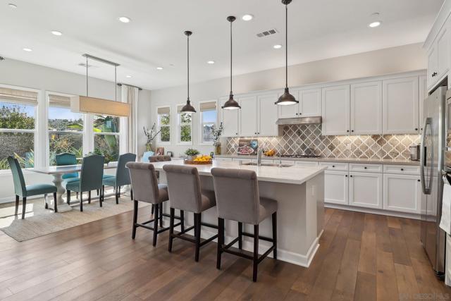 Stunning kitchen with marble island top, quartz prep space, and decorative stone backsplash covering the back wall.