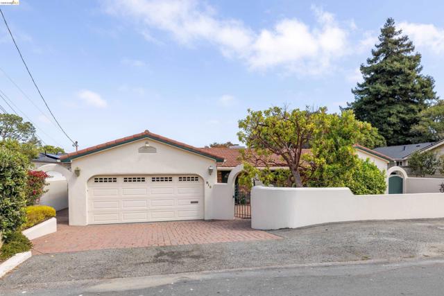 Stucco exterior with a tile roof, an integrated garage, a brick paver driveway, and a decorative privacy wall