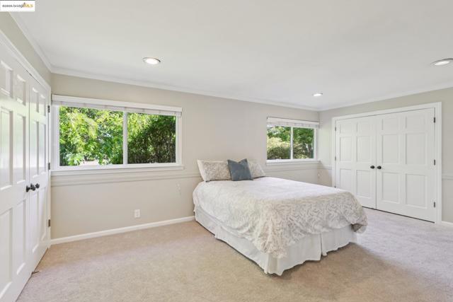 Bedroom with crown molding, light colored carpet, recessed lighting, and a closet
