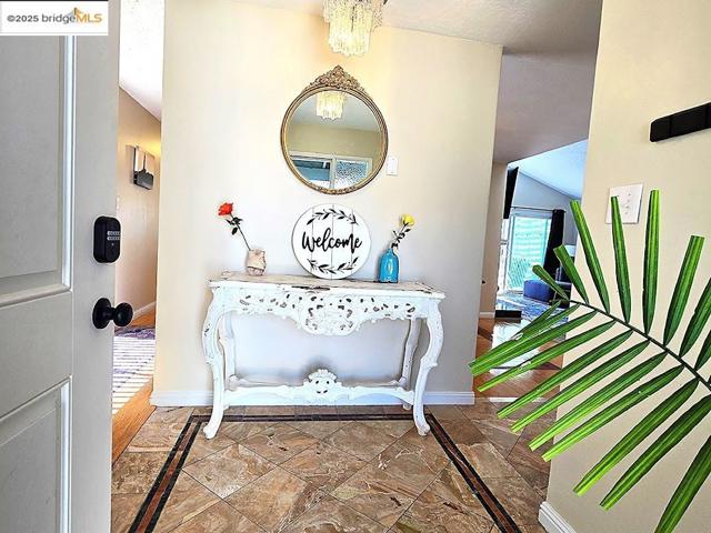 Entrance foyer featuring vaulted ceiling, inlaid floor details, and a chandelier