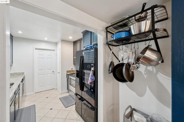 Kitchen featuring black fridge with ice dispenser, light tile patterned floors, stainless steel range with electric cooktop, light stone countertops, and recessed lighting