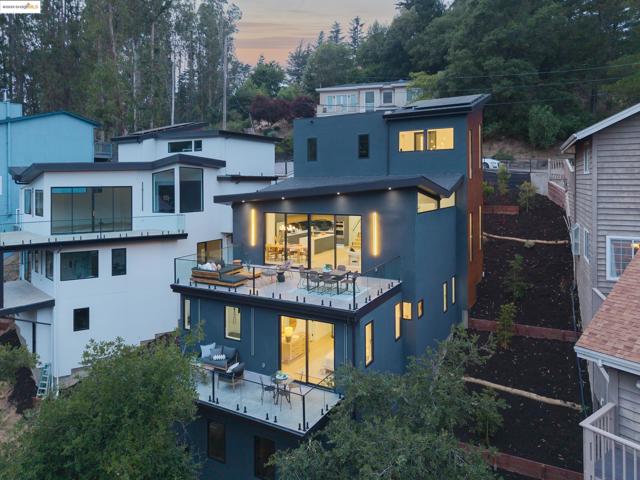 Back of house at dusk with a balcony, stucco siding, and view of wooded area