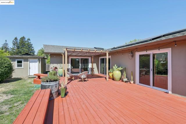 Deck featuring a pergola, a lawn, and a storage shed