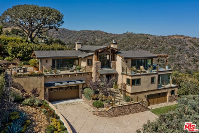 1266 Chautauqua Boulevard Pacific Palisades, California This private and gated panoramic view estate is unlike any other in the heart of the Palisades Village. The residence is set on an expansive promontory and features a stately stone facade, welcoming guests into the middle level. Via stairs or elevator, the top floor features a beautiful living room with fireplace that spills out towards the views and a recently redone island kitchen with top appliances. A formal dining room under elegant arches, family room, office, patio with firepit, and al fresco dining deck with BBQ and heaters finish the top level. Awe-inspiring views span from Will Rogers State Park to Downtown and Century City, to the jetliner views of planes landing at LAX below Palos Verdes, and the entire bay from Catalina to the edge of Malibu. The middle level features three ensuite bedrooms, including the master suite, with incredible views, a stunning bathroom with separate shower and tub, dual vanities, and a huge walk-in closet. The lower level is graced by a 700+ bottle wine cellar, tasting room, large laundry room, and a separate guest apartment outfitted with a living room, kitchen, bedroom, bathroom, and separate entry. The home is completed by two 2-car garages, walnut floors throughout, tankless water heaters, and a newer security/camera system. Completely rebuilt in 2006 by R&R Construction.