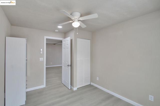 Unfurnished bedroom with light wood-type flooring, a ceiling fan, and freestanding 2nd closet.