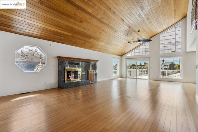 Unfurnished living room with wooden ceiling, a ceiling fan, hardwood / wood-style floors, a high end fireplace, and high vaulted ceiling