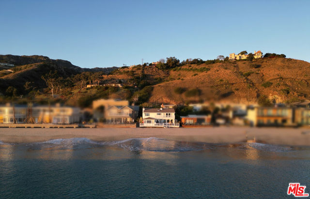 Nestled on Billionaire's Beach in Malibu, this inviting Cape Cod inspired home beckons with 55 feet of beach frontage, offering unparalleled views of rolling white water and the coastline. Recently enhanced with a new roof, gutters, skylights, exterior repairs, paint, and a bamboo fence, this residence is ready to embrace your beachfront dreams. As you enter through the gated courtyard the oversized spa tub invites you to unwind, providing a private sanctuary just steps from your front door. The main entrance reveals a living space bathed in natural light, drawing you towards breathtaking ocean views through expansive glass walls. The first floor seamlessly flows to a beachfront deck adorned with custom lounge chairs, a daybed, and a dining table, a perfect setting for enjoying the rhythm of the waves and the warmth of the sun. Imagine waking up to the gentle crash of the waves and stepping out your back door to feel the soft sand beneath your feet or taking a refreshing swim in mother ocean just steps from your bed. Inside, the living area, ocean-view nook, and wood-burning fireplace create a cozy atmosphere, while the Chef's kitchen invites culinary delights. The en-suite guest bedroom, powder room, and additional full bath provide comfort and convenience. Upstairs, the allure of beachfront living continues with a guest bedroom featuring a balcony for enjoying the salty breeze. The Primary Suite, with its own ocean-view deck and wood-burning fireplace, is a private retreat. This property isn't just a house; it's an invitation to experience the coastal lifestyle. Whether you choose to revel in the tranquility of the courtyard, bask in the sun on the beachfront deck, or indulge in the sheer luxury of direct beach access, this home is a haven for those seeking the ultimate beachfront experience. With Cross Creek, Nobu, and Soho House in walking distance, you'll enjoy the convenience of city amenities in a tranquil seaside setting. Embrace the allure of Malibu living and make this beachfront retreat your own.