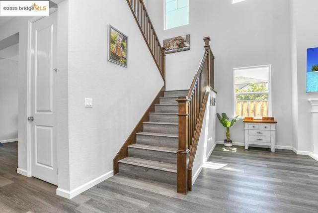 Stairs with wood finished floors and a towering ceiling