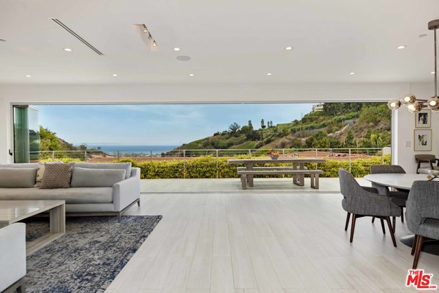 1332 El Hito Circle Pacific Palisades, California Gazing out towards unobstructed ocean views framed by mountains and vineyards, this single-level architectural residence was completely remodeled and expanded in 2017. Past a tranquil waterfall, guests are welcomed by an open floorplan into the main living space with a gorgeous living room, island kitchen with top appliances, and dining area, leading out via glass retracting doors to the breathtaking views. The outdoor spaces are a perfect combination of grass yard, entertaining patio, large spa, and sport court-all with ocean and hillside/vineyard views. The five bedrooms are well laid out, including the private primary bedroom with ocean views, multiple closets, and large bathroom with an oversized shower and dual vanity. The combination of gorgeous stone and wood design details with the abundance of natural light through massive skylights make this indoor/outdoor home a prime example of Southern California living.