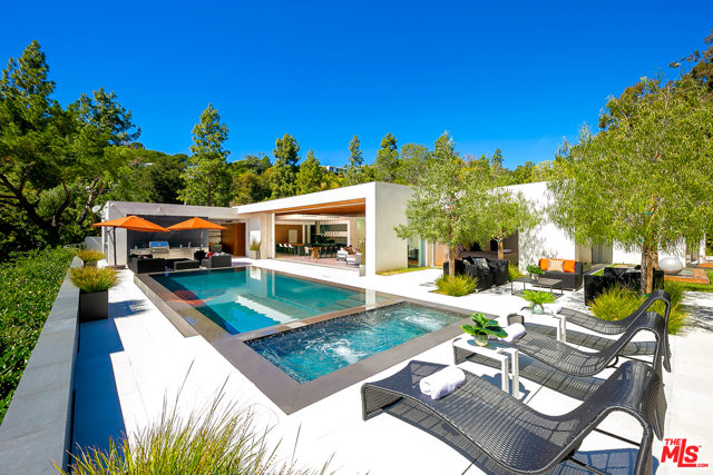 1120 Loma vista Drive Beverly Hills, California Located in one of the most coveted neighborhoods of Los Angeles, this property is a masterpiece of light and design. The gated motor court leads to an oversized pivot door which opens into a dramatically walled hallway gallery. This gorgeous single-story modern marvel features impeccable high-end finishes including an owners suite showcasing Snaidero closets, wellness spa, and a Yoga deck off the suite, Fleetwood vanishing walls of glass, grand-scale chefs Bulthaup kitchen with Gaggenau appliances, and a stunning 600-bottle wine wall, multi-zone interior/exterior sound system. The Kalamazoo outdoor kitchen perfectly complements a zero-edge pool/spa and the private grounds with their lavish views down into the City of Beverly Hills and beyond. This estate is a true embodiment of the Southern California indoor/outdoor lifestyle living. Conceived by Urban Architecture Lab, completed in 2018 with a GSF of 8,500.