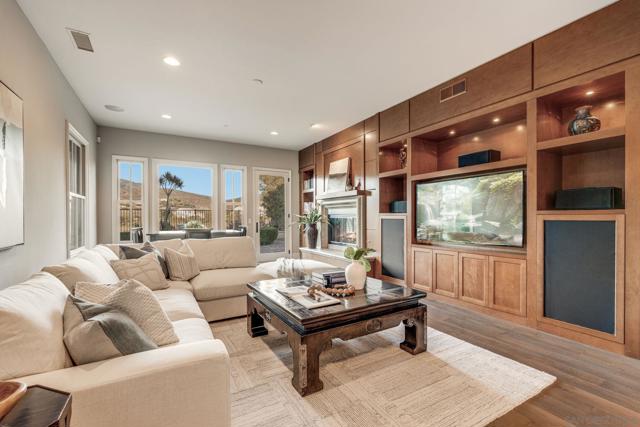 Spacious family room featuring custom built-ins, a cozy fireplace, and large windows that fill the space with natural light. French doors open to the backyard, creating a seamless indoor-outdoor flow—perfect for relaxing or entertaining.