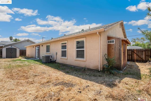 Back of property with a storage shed and stucco siding