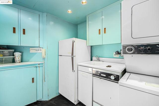 Kitchen featuring stacked washer / dryer, light countertops, freestanding refrigerator, and recessed lighting