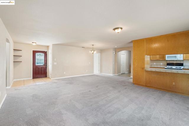 Unfurnished living room with arched walkways, light colored carpet, and a chandelier