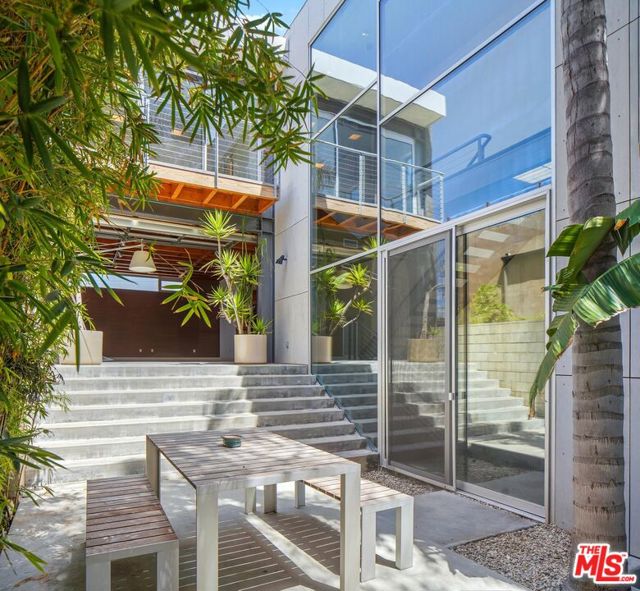 35 SUNSET Avenue Venice, California Modern Industrial masterpiece by Steven Ehrlich, on a walk-street half a block from the beach. This Venice home captures minimalist sophistication and the true essence of indoor/outdoor architecture. Exposed elements include concrete, steel, and wooden beams. Optimal light entry through multiple glass exteriors such as the roll-up garage doors in the living spaces which open to the front yard and central courtyard. Chefs' kitchen w/ stainless steel appliances, and wooden cabinets, island, plus open shelving; across from the built-ins surrounding a sleek fireplace in the living room. Additional family room on main level w/ own bathroom. All 3 bedrooms on the second floor, facing west. Primary suite features ocean views, fireplace, dual closets, double sinks, bath with separate shower & spa tub. Two additional bedrooms share the third bathroom. Another flight of stairs leads to an entertaining roof deck with its very own fireplace, surrounded by expansive ocean and city views.