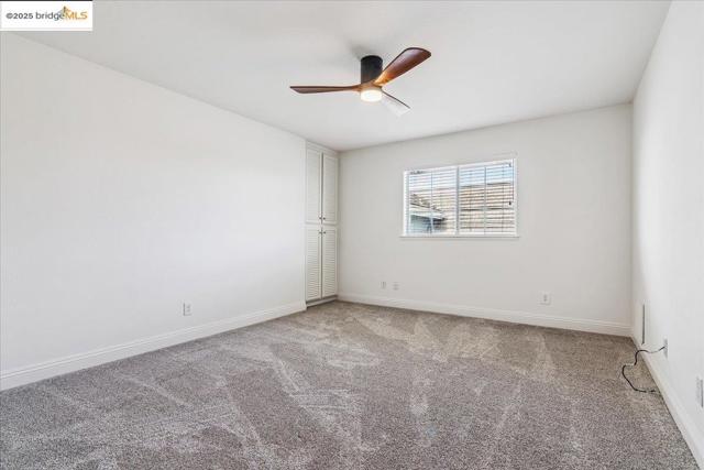 Carpeted spare room with a ceiling fan and baseboards