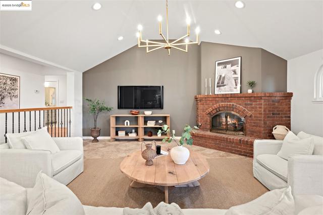 Living room featuring a fireplace, lofted ceiling, recessed lighting, and a chandelier