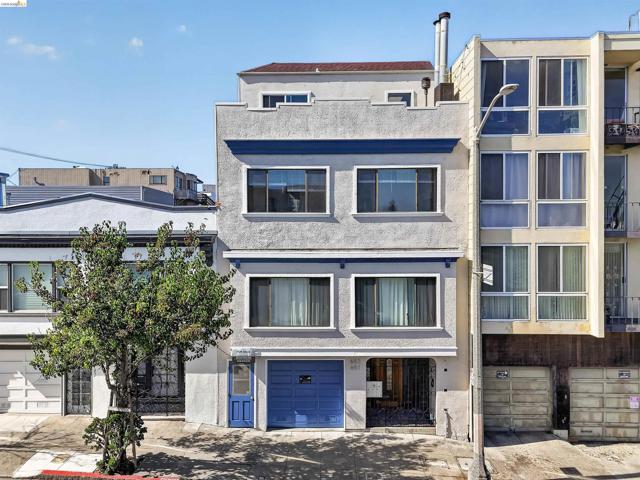 Multi-story stucco exterior featuring a flat roofline, integrated garage, decorative blue trim, and inset entry portal