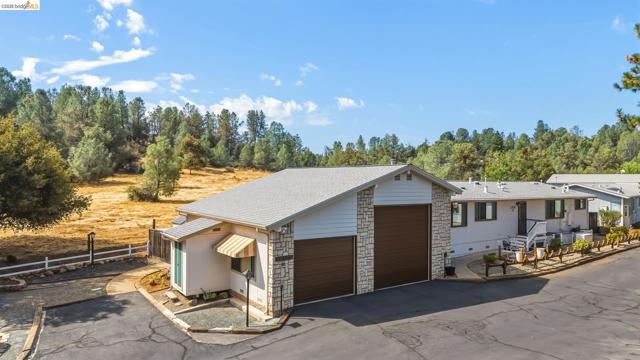 Attached garage structure with two bay doors, stone veneer accents, and asphalt driveway