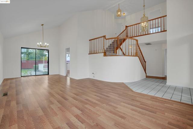 Unfurnished living room with a chandelier, high vaulted ceiling, and light wood finished floors