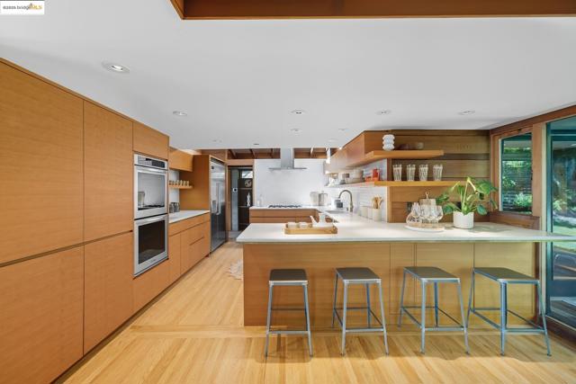 Kitchen featuring open shelves, a peninsula, modern cabinets, light wood finished floors, and a kitchen bar