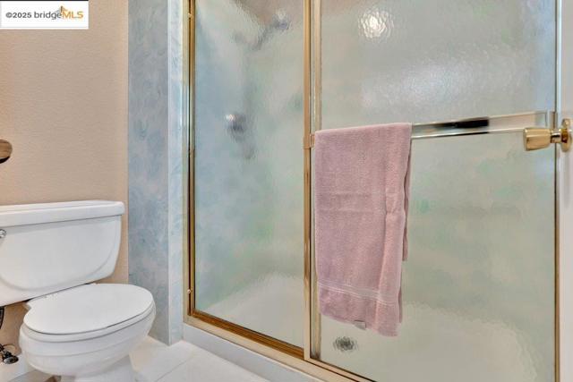 Full bath with a stall shower, tile patterned flooring, and a textured wall
