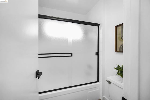 Bathroom with shower / bath combination with glass door and toilet