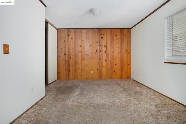 Carpeted empty room with wood walls and crown molding