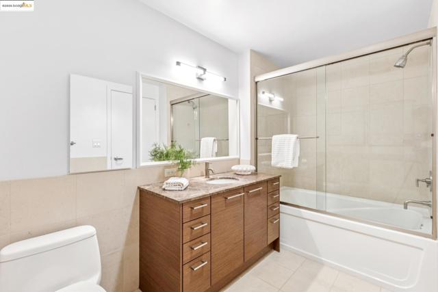 Full bath featuring vanity, bath / shower combo with glass door, tile walls, and tile patterned floors
