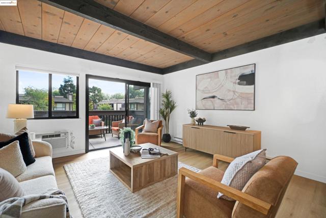 Living room featuring a wooden ceiling with exposed beams, wood finished floors, and a wall unit AC