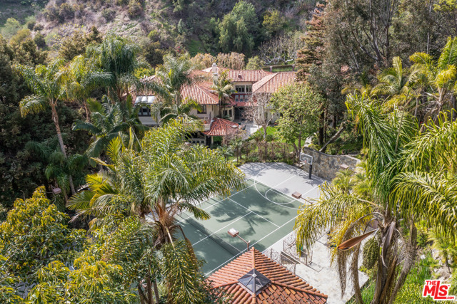 1290 Moraga Drive Los Angeles, California Behind the exclusive guard gates of Moraga Drive, just moments from Sunset/405, we present this picturesque Mission-Style Bel Air hacienda, situated on a quiet, private & pastoral 8.5 acre tree-studded parcel. This appx. 9,240sf estate offers all the luxuries & features for today's "home as resort" lifestyle, incl. generous, well-scaled public gathering & entertaining spaces, a lrg chefs kit w/informal dining, massive screening rm, game rm, private dual home offices/library, up to 5 bds in main res., each w/en-suite baths, incl. a baronial primary suite w/ multiple walk-in closets, reams of custom storage & dual luxurious indulgent baths. In addition, a separate full 1 bed/1 bath guest apartment w/private great rm, large bdrm & kit. Extensive millwork, stone & wood flrs, all new windows/glass patio drs high beamed/coffered ceilings, low voltage systems, dual fuel house-wide generator & pages of addtl. details/features. Entertain family or hundreds from entire 1st flr flowing easily to grassy garden areas, patios, mltpl outdoor kit/BBQ areas, a hotel-size lagoon-style pool, tennis court + pavilion. Endless trails & original monorail track for adventures past 3 waterfalls into a multi-acre botanical wonderland. Impressive frontage w/rich, textured curb appeal, 4-car garage & circular motor ct complete this rare assemblage. Escape, retreat, wander & enjoy