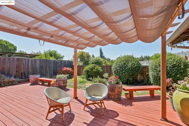 Wooden deck with a pergola and a fenced backyard