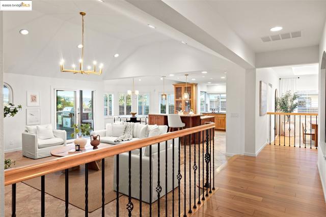 Living room with a chandelier, healthy amount of natural light, light wood-style flooring, recessed lighting, and lofted ceiling