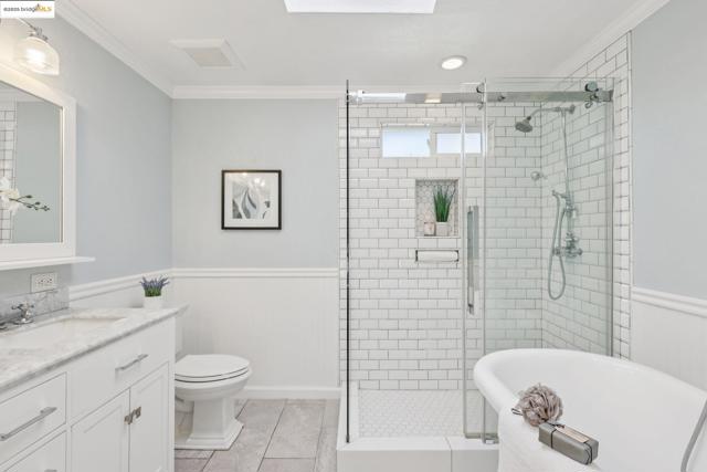 Full bath with wainscoting, ornamental molding, vanity, a soaking tub, and a shower stall
