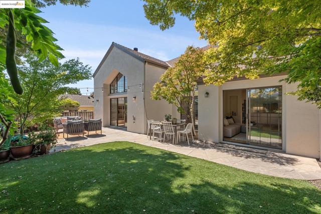 Back of house featuring stucco siding, a patio area, outdoor lounge area, and a lawn