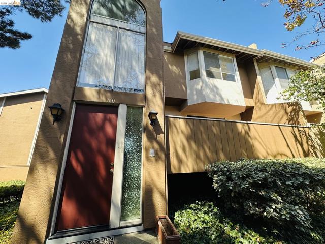 Arched window detail, red front door, textured stucco exterior, exterior wall sconces, integrated landscaping