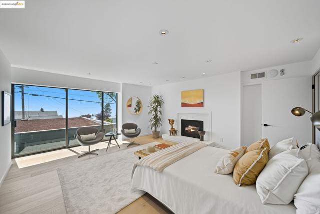 Bedroom with recessed lighting, light wood-style floors, a lit fireplace, and access to exterior