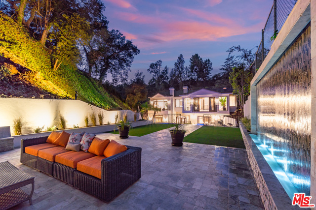 2650 Hutton Drive Beverly Hills, California Encompass a lifestyle filled with luxury, entertainment, and tranquility in this approx. 5,600 sqft legacy estate with nearly 1/2 acre corner lot featuring prominent indoor & outdoor living space. Upon the grand entrance, the abundant natural light welcomes you into the expansive porcelain tiled living, dining and relaxing rooms while tempting you into the intimate stacked-stone wine tasting area or the private artist creative space. After working in your home-office or private security room, the great bamboo fitness room is just steps away from a rewarding steam or cinema experience, or an ivy-covered hillside for ultimate privacy in your pool, jacuzzi, or immense terrace featuring a 20 Ft mosaic tiled waterfall. Perhaps the massive master suite overlooking the impressive plaza & lush florae, sitting by 1 of the 5 fireplaces or tapping a hole in one on your own putting green is a welcomed nightcap. This legacy estate exemplifies connection and luxury for experiences to be made.
