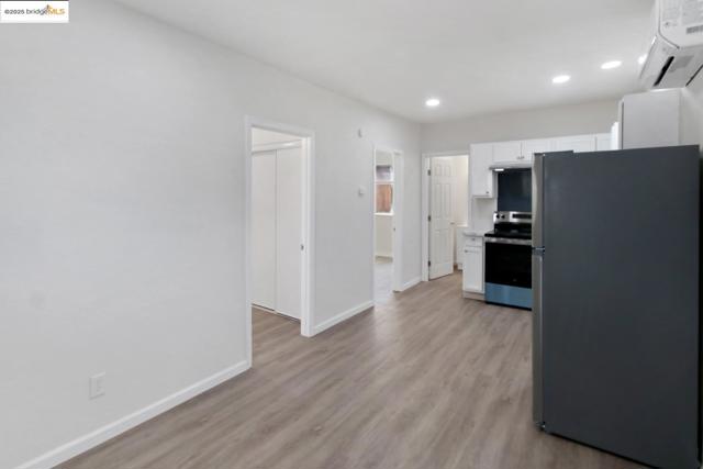 Kitchen featuring stainless steel appliances, white cabinets, a wall unit AC, light wood-style flooring, and recessed lighting