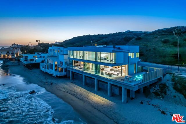 World class all new contemporary masterpiece ideally located on famed Malibu Road beach! Set on approximately 100 feet of prime ocean frontage with a sought after pool and spa. Fire pit and additional spa on the Ipe wood roof top deck. Push a button and the walls of glass disappear leaving only the glass railings between you and the Pacific! Wide open concept design leads you to view the tide pools or the surfer's beyond! Walnut wood interior, heated porcelain floors throughout, built on 27 caissons that go 60 feet anchored to solid bedrock. The master bedroom and main floor capture unobstructed ocean vistas. Watch the coast light up at night and the "Queens necklace" view sparkle! World renowned shopping and restaurants a short jaunt away! Be the first to occupy this exquisite offering!