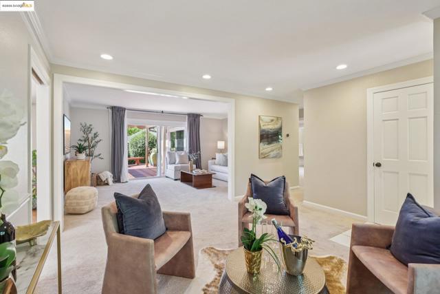 Living area with light colored carpet, ornamental molding, and recessed lighting