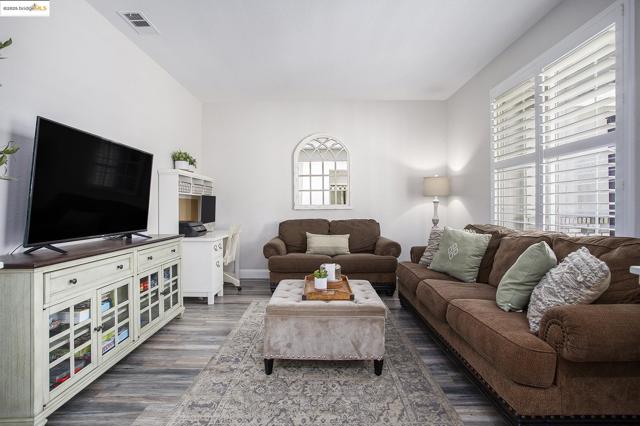 The living area is private, but still offers an open concept. Featuring laminate wood finished floors, baseboards, and shutters