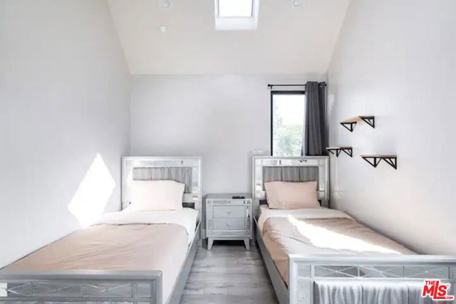 Bedroom #6 has two twin sized beds, a night stand, and shelves