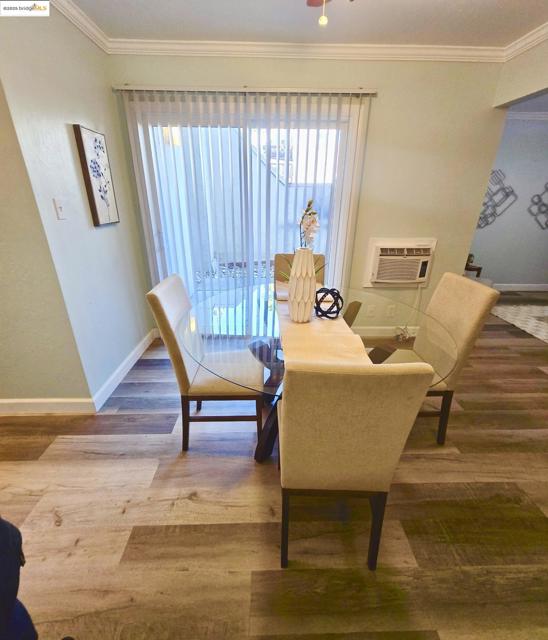 Dining space with crown molding, wood finished floors, and a wall mounted air conditioner