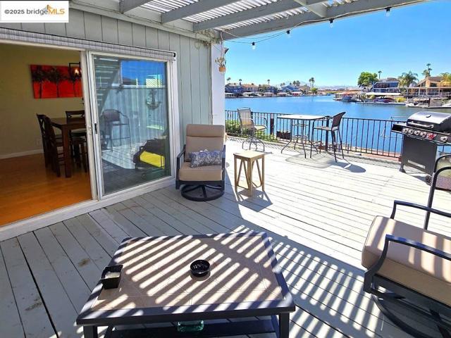 Wooden terrace featuring area for grilling and a water view